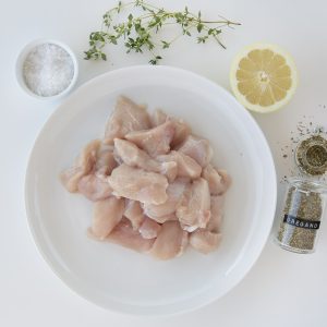 Diced chicken with salt, thyme, lemon half and a jar of oregano spices